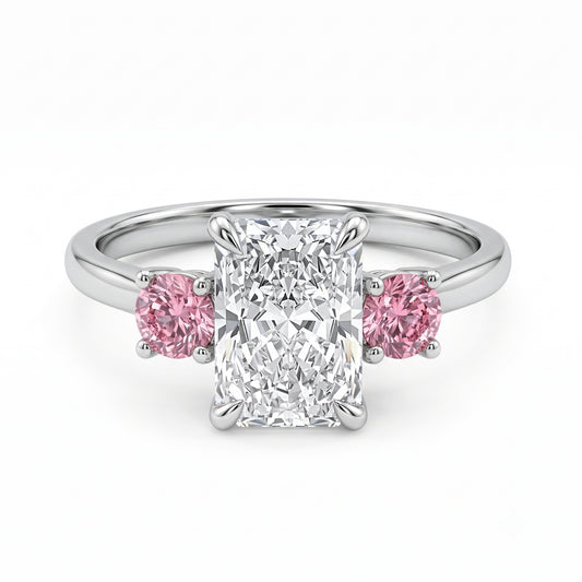 A three stone diamond ring featuring Radiant cut diamond flanked by two round pink Spinel  set in a trilogy style. 