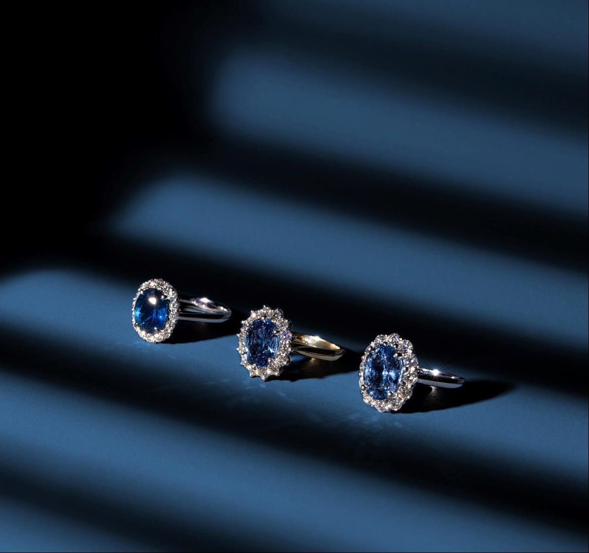 Three ceylon sapphire rings with diamonds on a dark surface