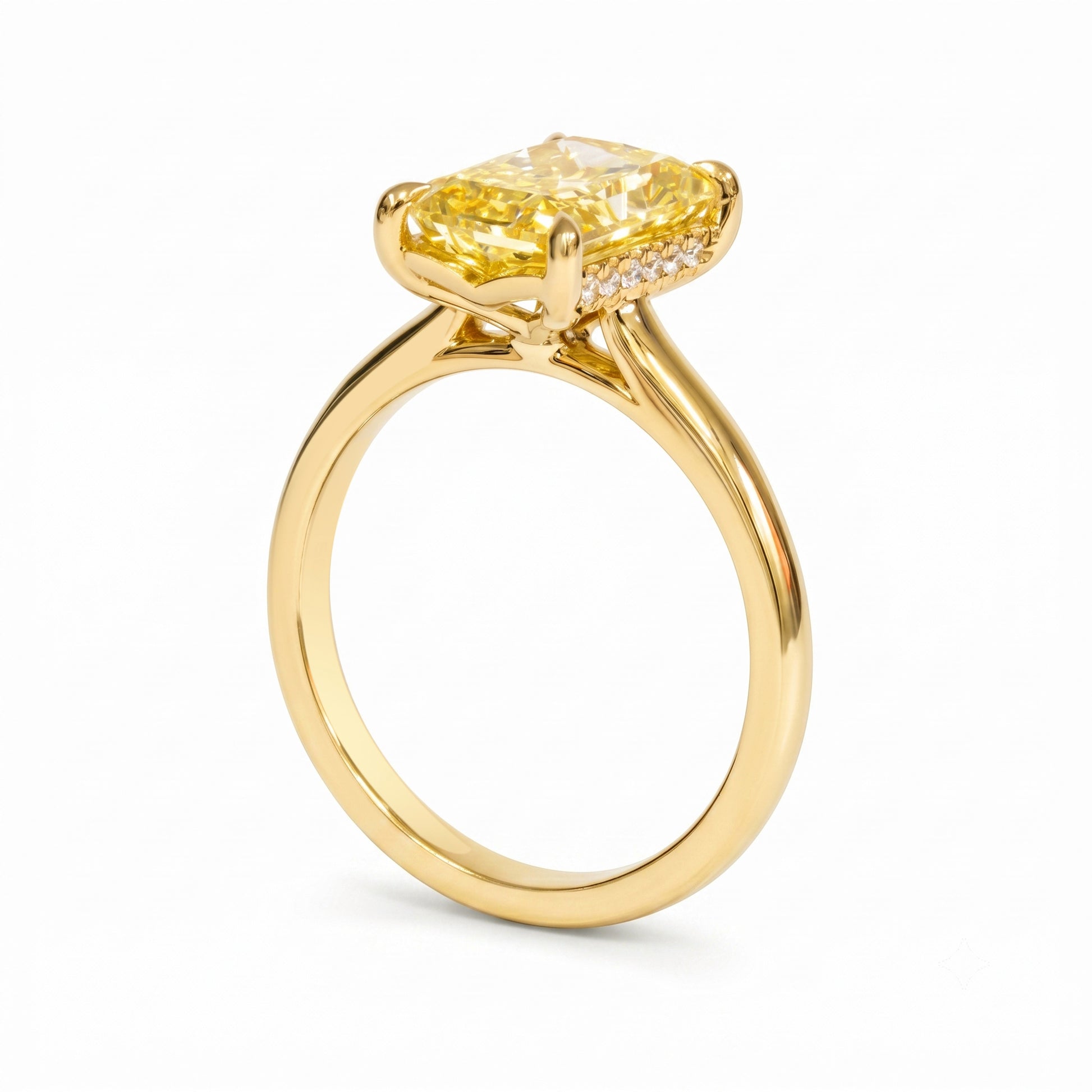 A yellow diamond engagement ring in a polished yellow gold setting, featuring a cushion-cut center stone and a halo of small accent diamonds on a clean white background.