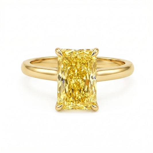 A yellow diamond engagement ring with a rectangular radiant-cut center stone in a four-prong setting on a polished yellow gold band, shown against a plain white background.