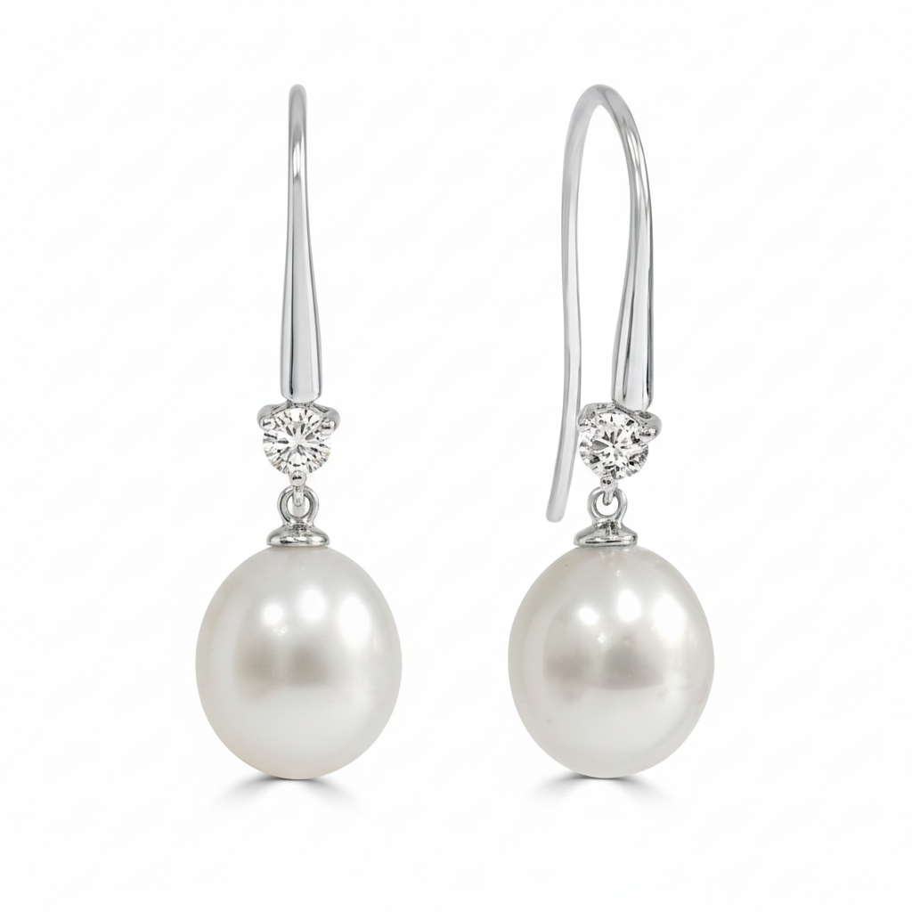 A pair of white gold drop earrings featuring a round south sea pearl and a small diamond shepards hooks.