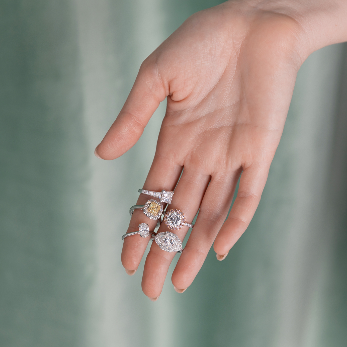 A woman's outstretched hand showcases five diamond engagement rings
