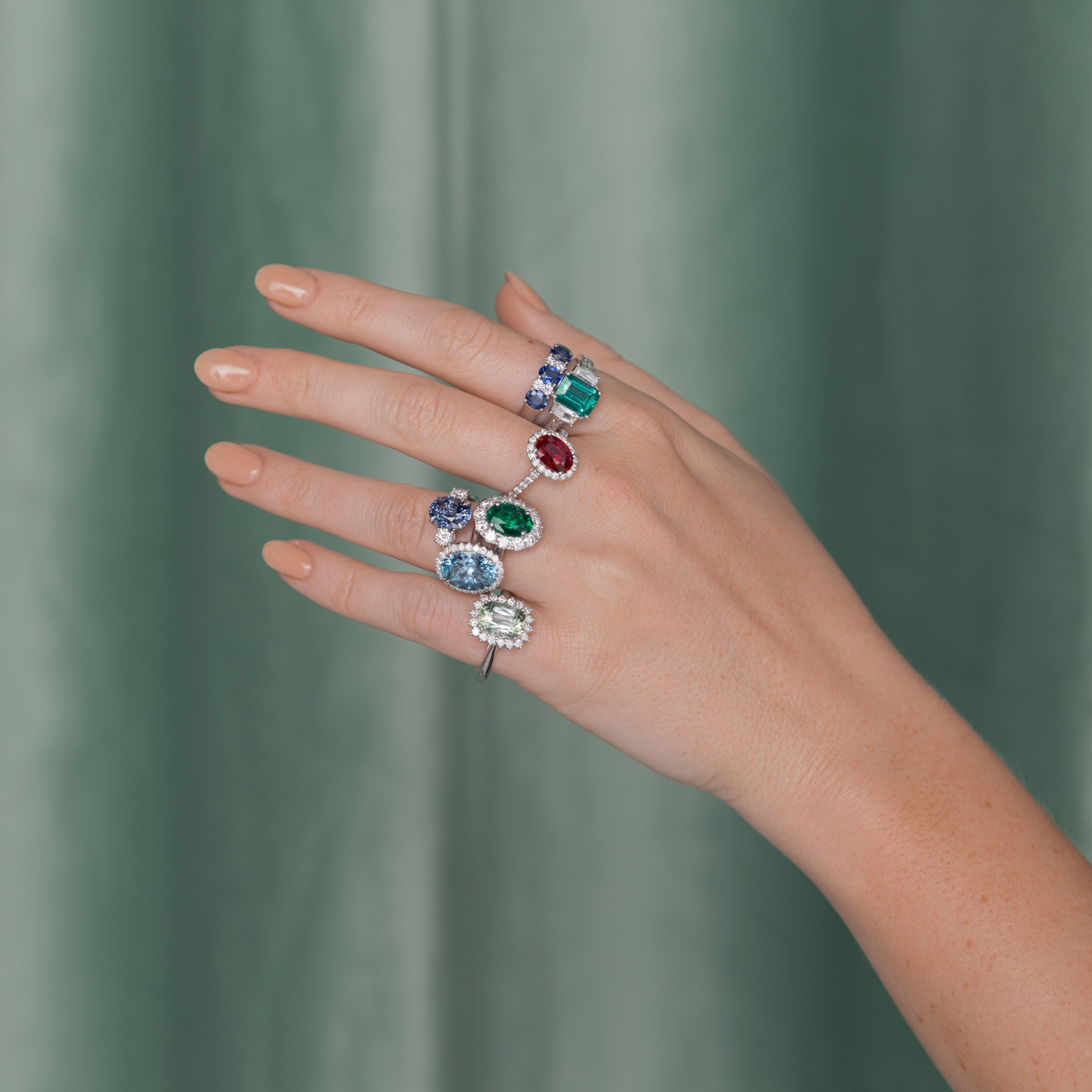 A woman's outstretched hand showcases a selection of Coloured stone rings