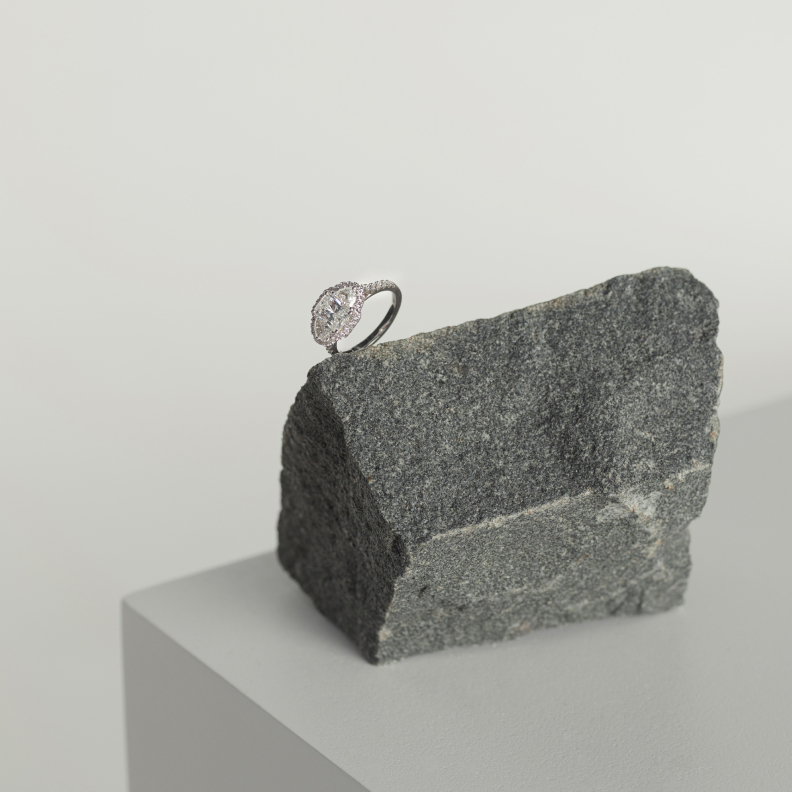 A stunning white gold diamond engagement ring sits upon a dark natural stone