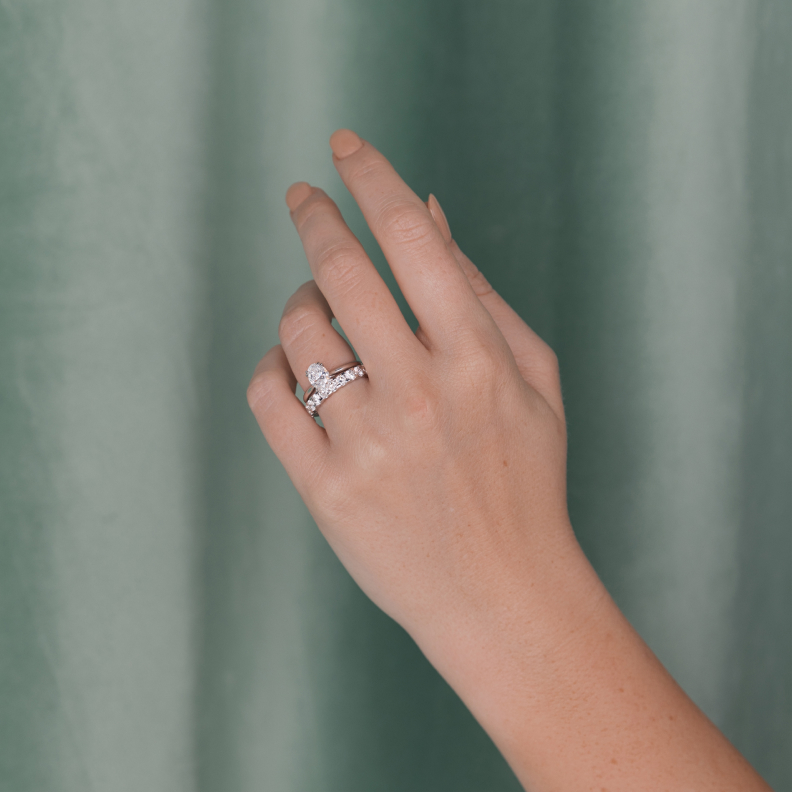 A woman's outstretched hand showcases a diamond wedding band and a diamond engagement ring