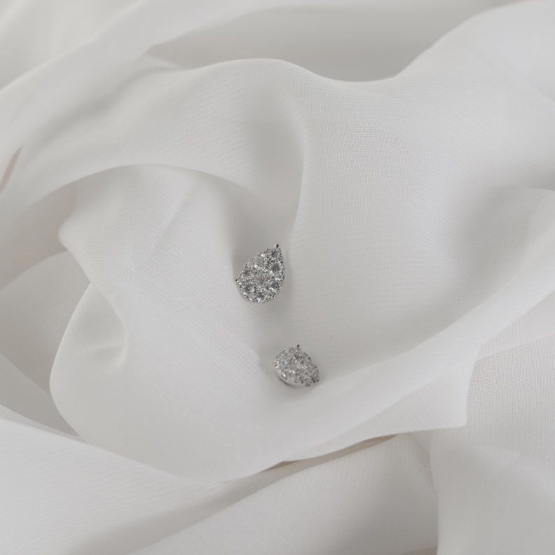 White Diamond stud earrings resting on white silk