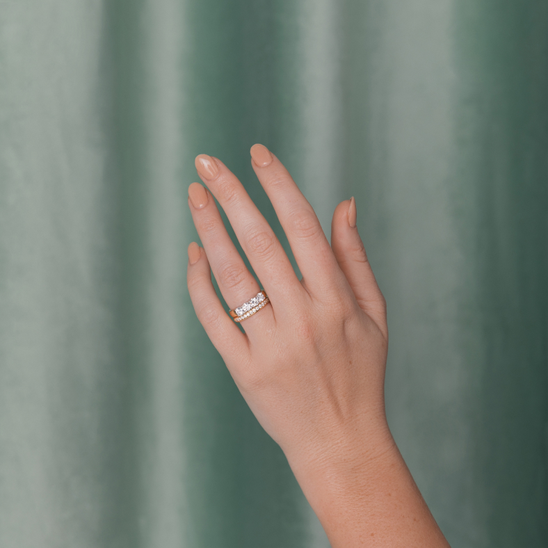 A woman's outstretched hand showcases a diamond wedding band and a diamond eternity ring